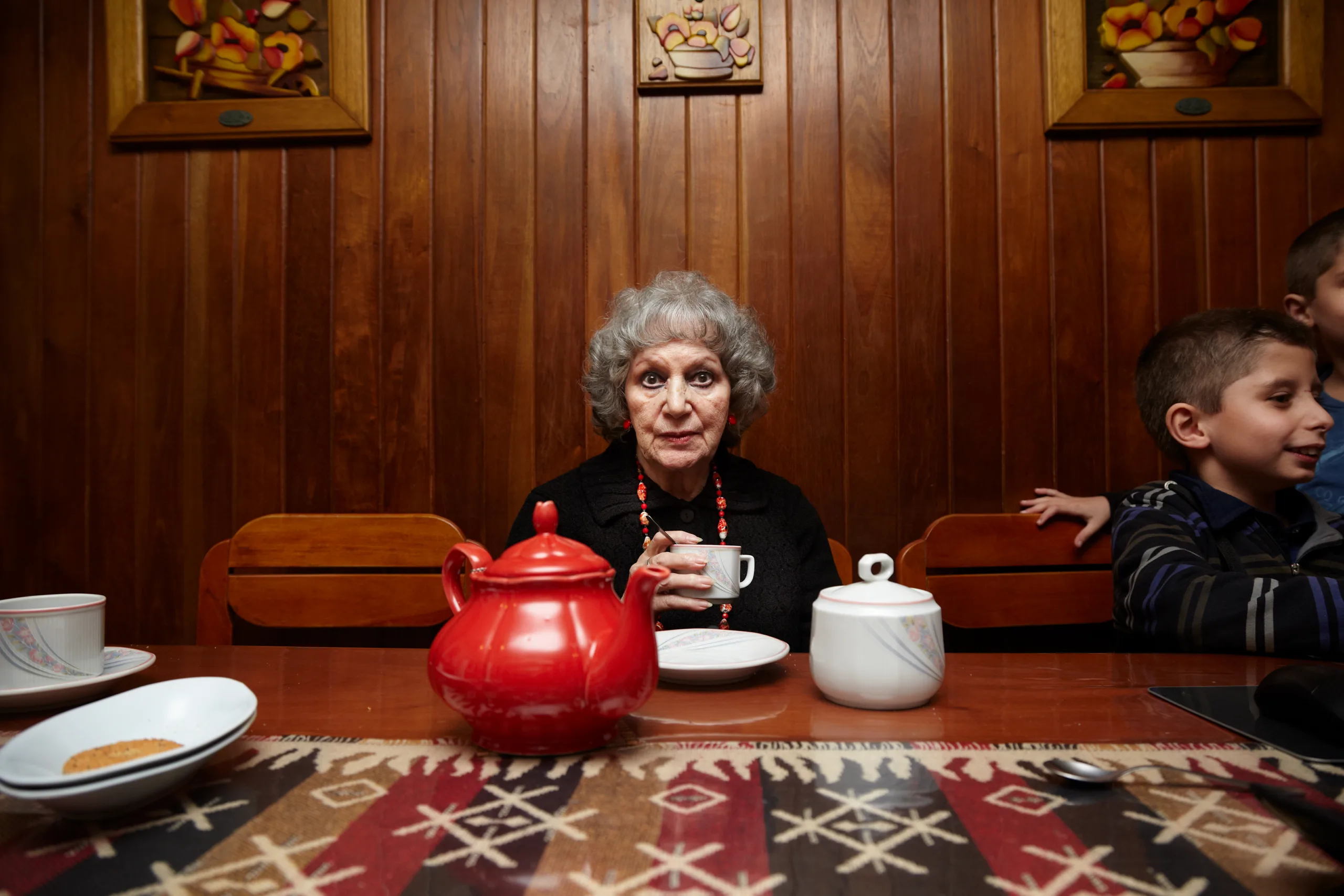 The Great grandmother drinking tea at the family table, with her grandchildren beside her, The Flowers Family documentary series, Argentina